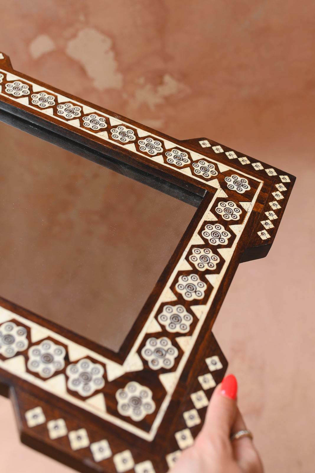 Angled view of bone and wood marquetry on Damascus mirror frame
